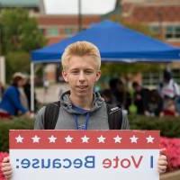 Student holding sign titled "I vote because: my vote matters"